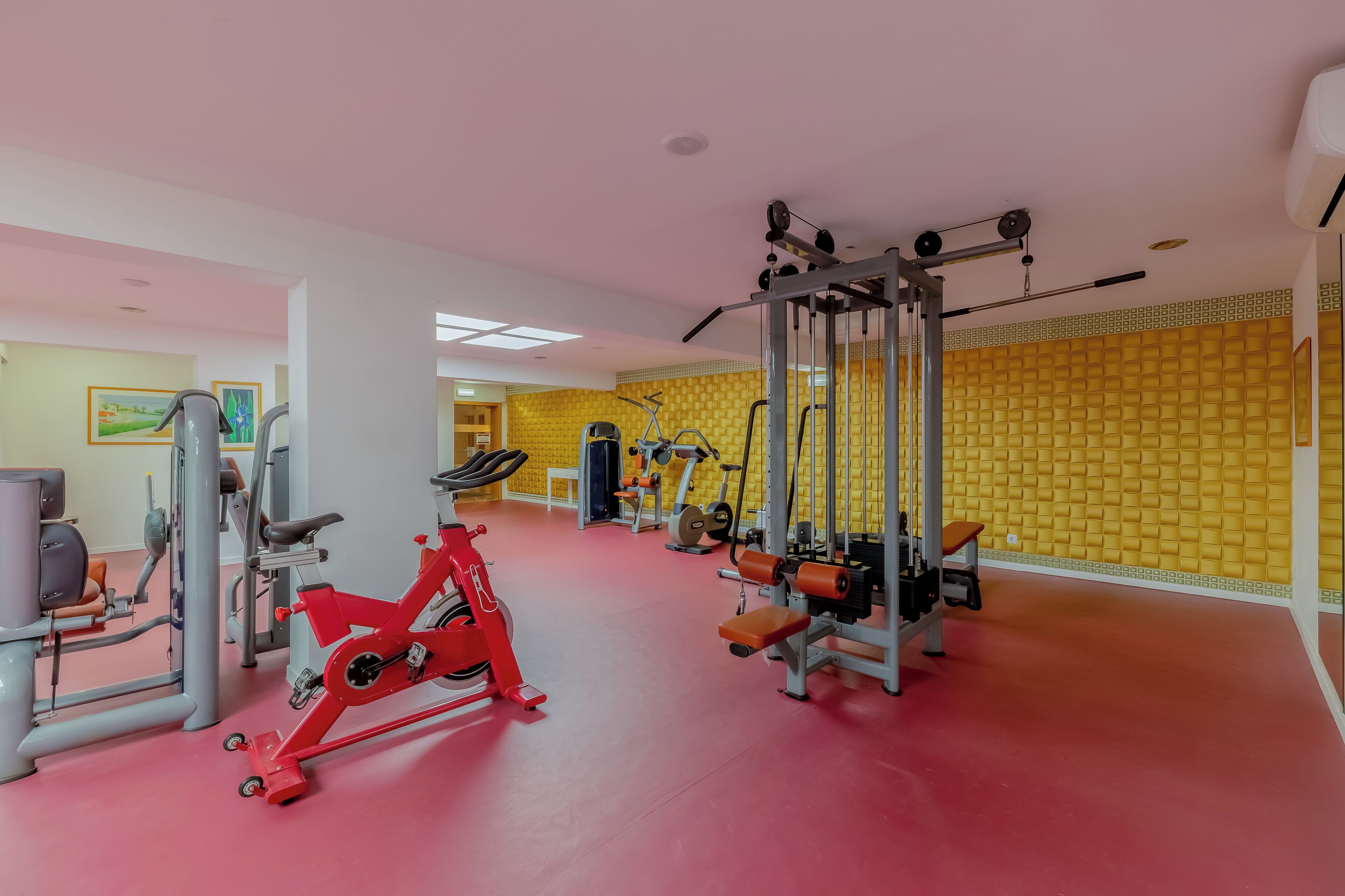 A gym with various exercise equipment, including a red stationary bike and weight machines.