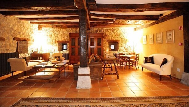 A rustic interior with exposed wooden beams, stone walls, a fireplace, and traditional furnishings. - Hotel Casona de Quintana (Soba)