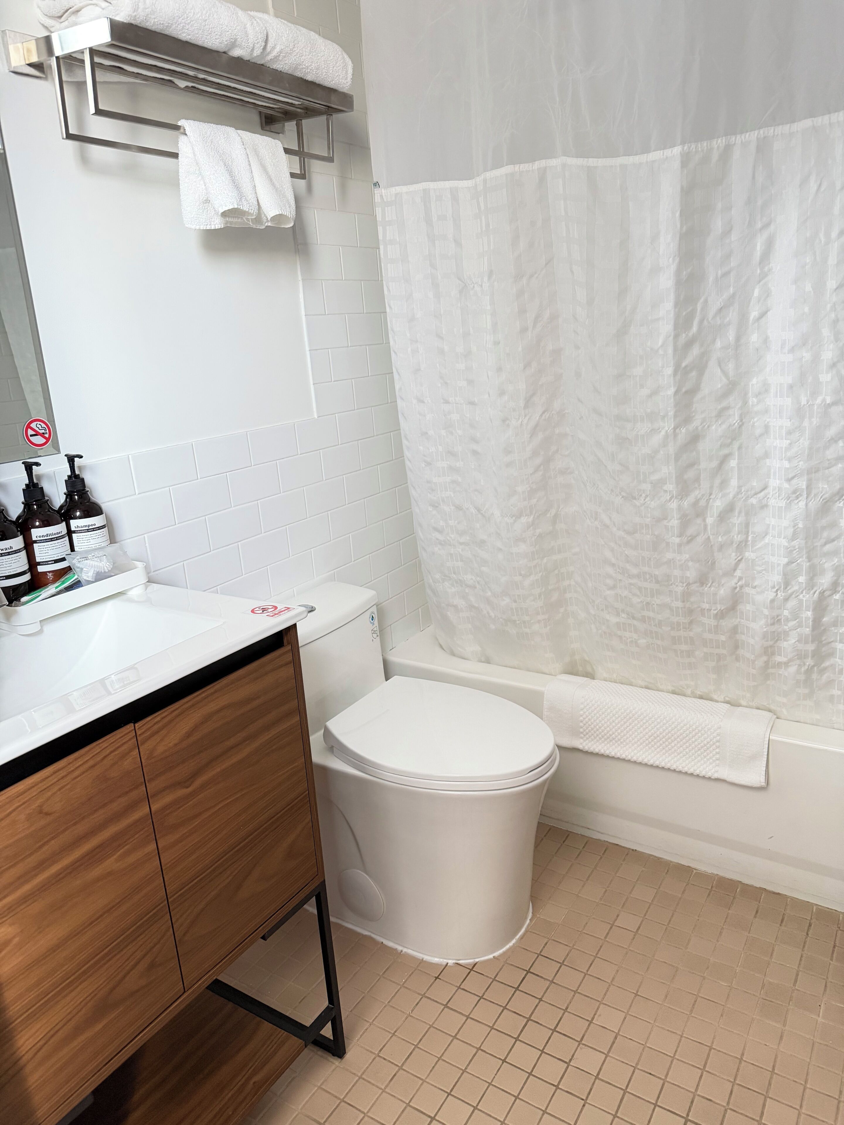 A bathroom with a white toilet, a sink with toiletries, and a shower curtain.