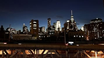 Un horizonte urbano nocturno con edificios iluminados y un puente en primer plano.