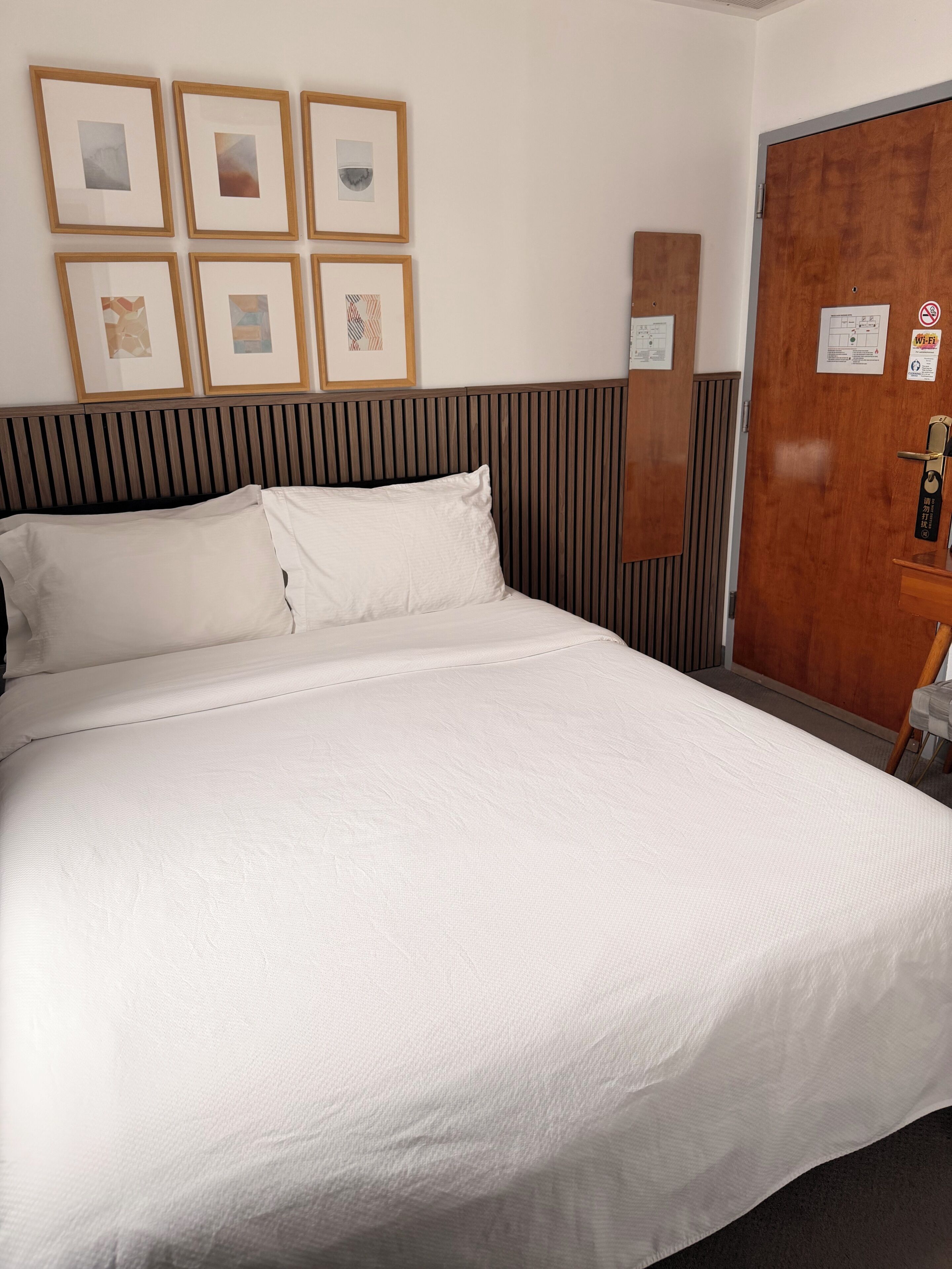 Habitación de hotel con una cama grande, cabecera de madera y cuadros en la pared.
