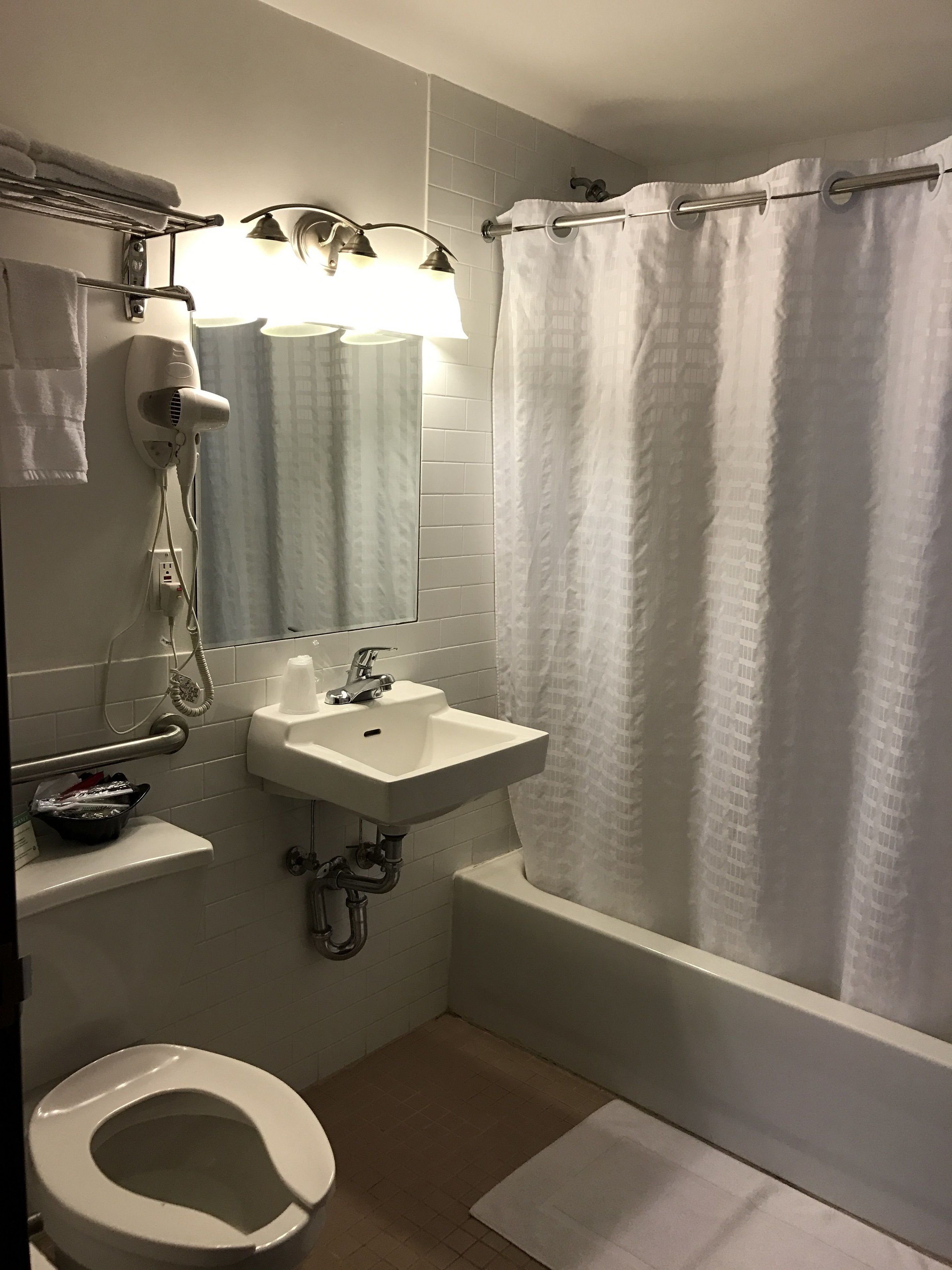 Un baño con lavamanos blanco, inodoro, secador de pelo y cortina de ducha.