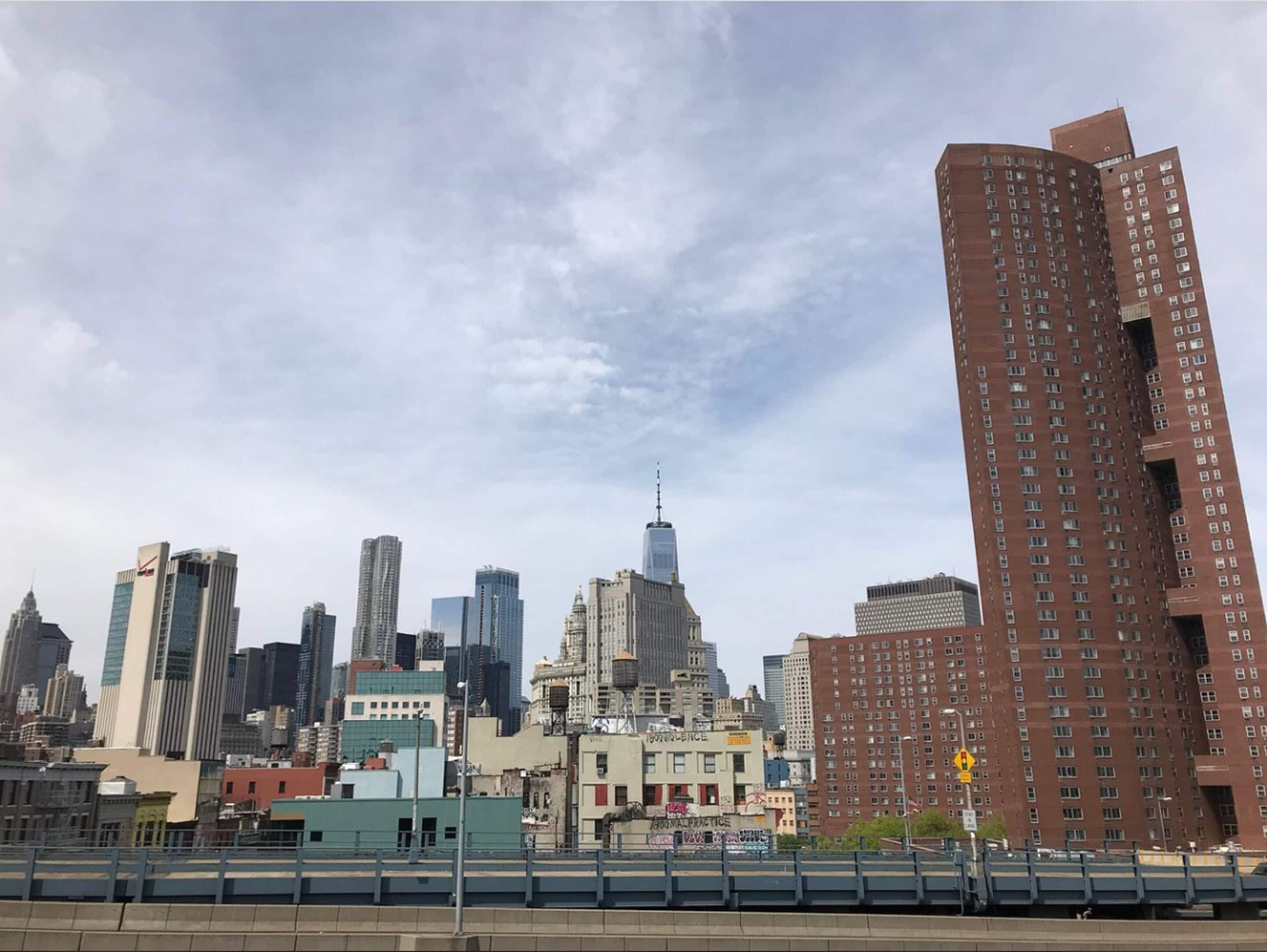 A city skyline with various high-rise buildings, including a prominent skyscraper with a spire.