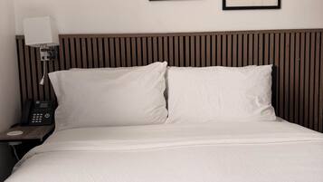 Una camera d'albergo con un letto, un comodino con un telefono e tre opere d'arte incorniciate appese al muro.