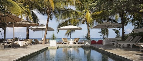 Una piscina al aire libre, sombrillas, sillones reclinables de piscina