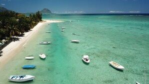 A beach with clear turquoise water, several boats, and a sandy shore lined with palm trees. - The Bay (Black River)