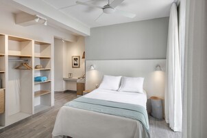 Una habitación de hotel moderna con una cama grande, armario empotrado, lámparas de noche y un ventilador de techo.