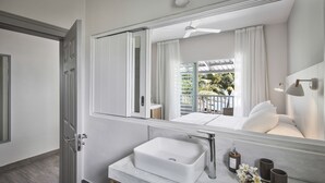 A modern bathroom with a large mirror, a white sink, and a shower area. - The Bay (Black River)