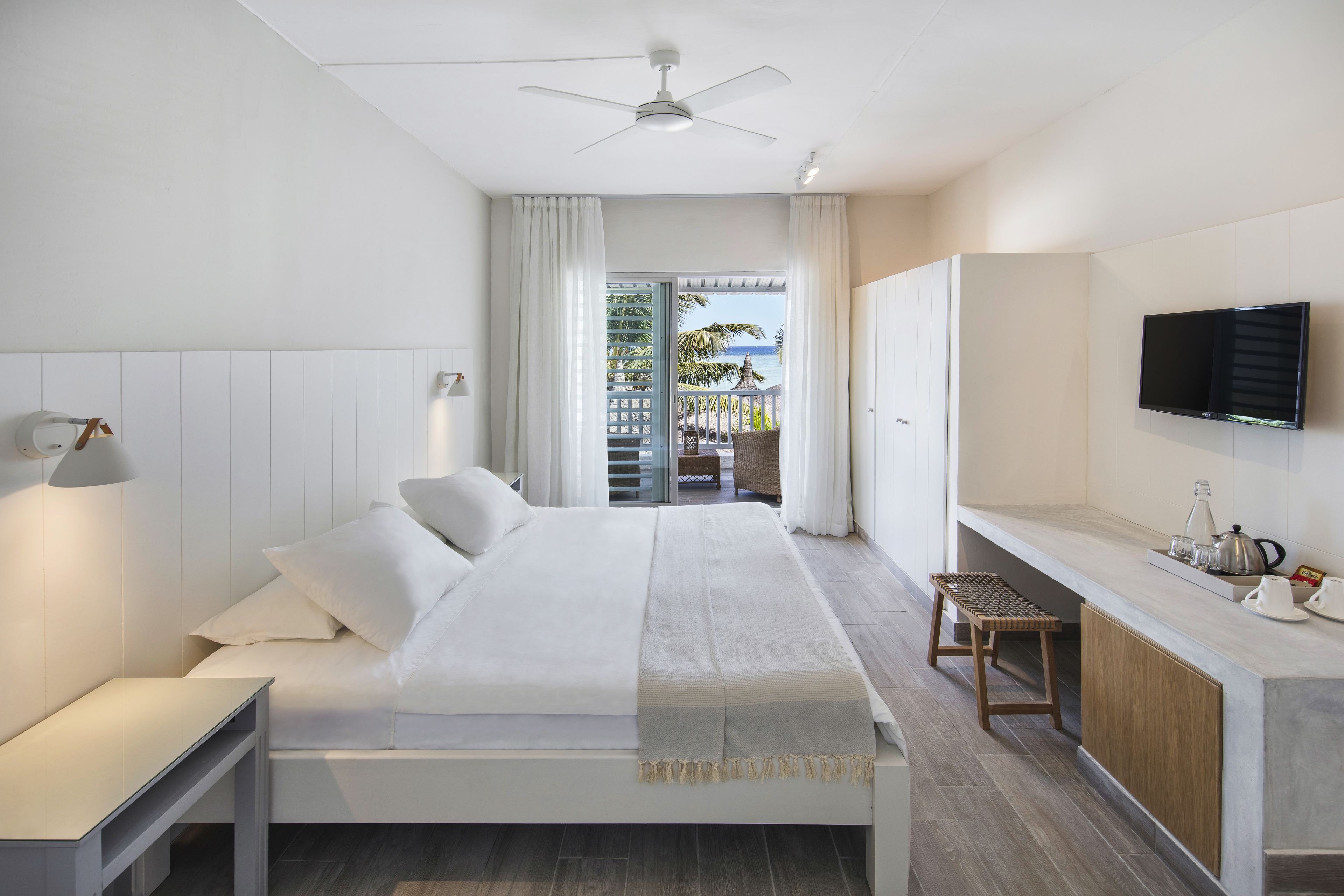 A modern hotel room with a bed, bedside table, and a TV mounted on the wall.