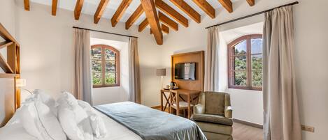 Une chambre à coucher avec un lit, un bureau, une chaise et deux fenêtres avec des rideaux.