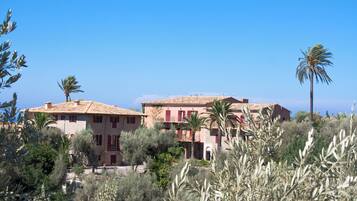 A Mediterranean-style villa with terracotta roofs, multiple balconies, and lush greenery.