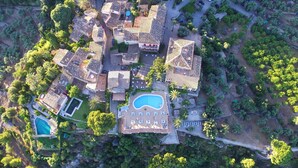 Vista aérea de un área residencial con varias casas, una piscina y vegetación circundante.