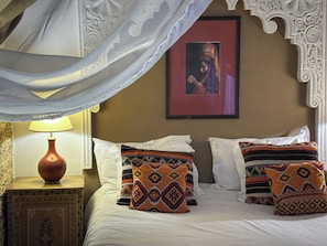 A bed with patterned pillows, a bedside lamp, and a framed picture on the wall.