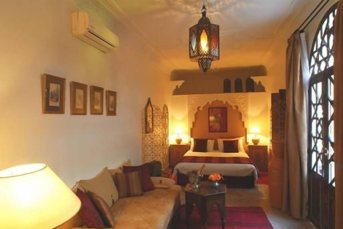 A cozy hotel room with a bed, a sofa, a coffee table, and a decorative wall.