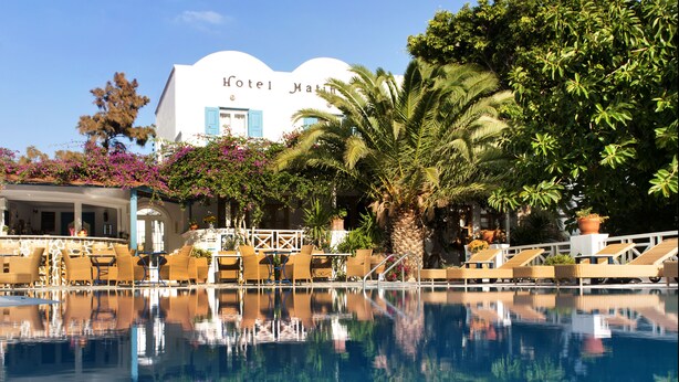 A hotel with a pool reflecting the building and surrounding trees.