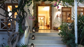 A staircase leading to a wooden door with a hanging lantern, surrounded by greenery and potted plants.