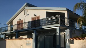 A two-story house with a balcony, a gate, and a small sign on the wall. - Perla del Sole (Syracuse)