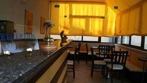 A reception area with a counter, chairs, and a window with curtains. - Perla del Sole (Syracuse)