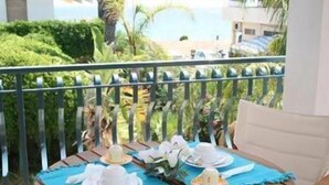 A balcony with a table set for two, overlooking a pool and greenery. - Perla del Sole (Syracuse)