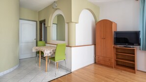 Quarto com mesa de jantar, cadeiras, televisão e guarda-roupa.