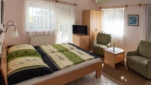 Quarto com cama, televisão, cadeira e escrivaninha.