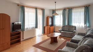 Uma sala de estar com sofá, poltrona, aparador de madeira e televisão.