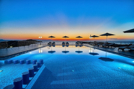 Una piscina al aire libre, sombrillas, sillones reclinables de piscina