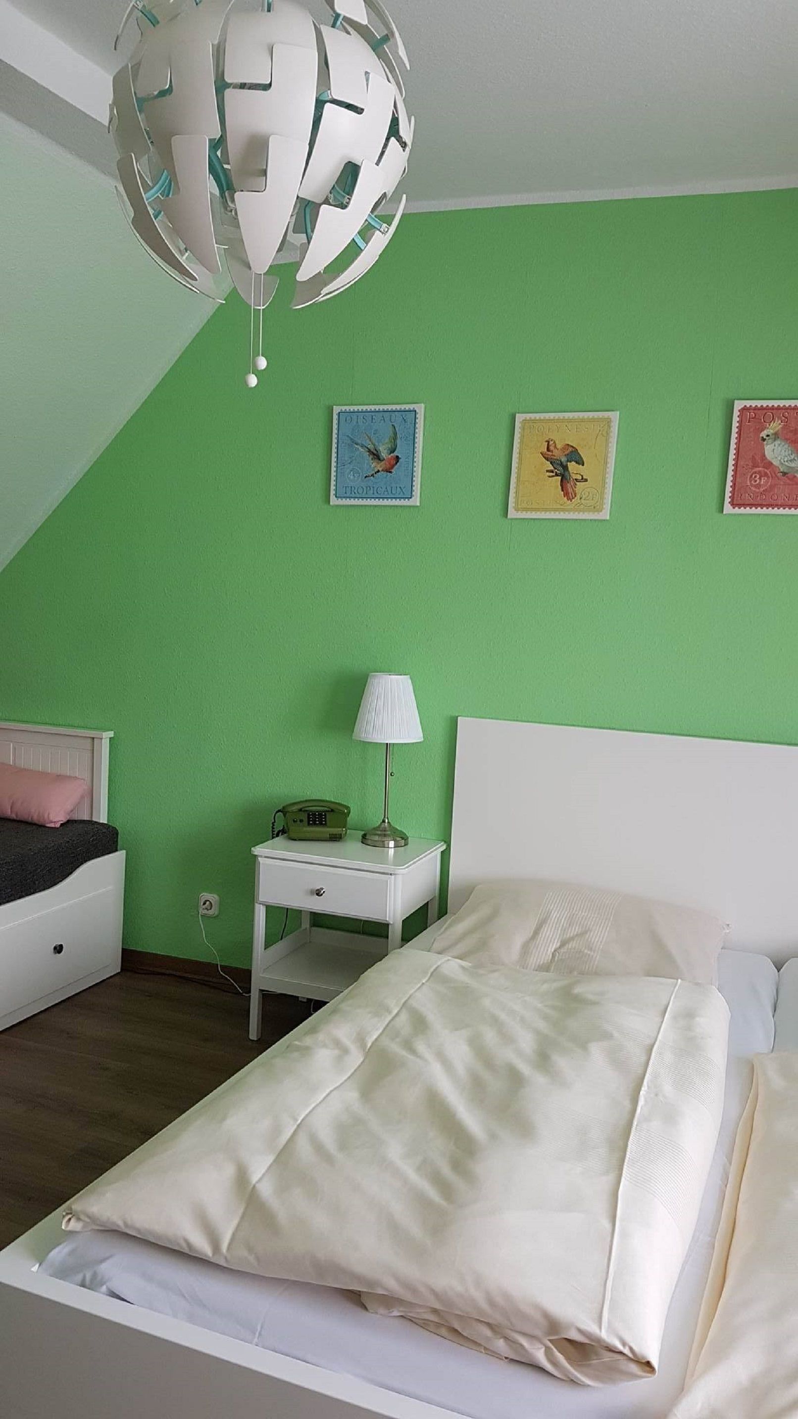 Un dormitorio con cama, mesita de noche, lámpara y decoración en la pared.