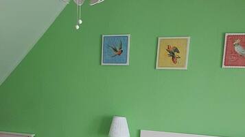 Un dormitorio con cama, mesita de noche, lámpara y decoración en la pared.
