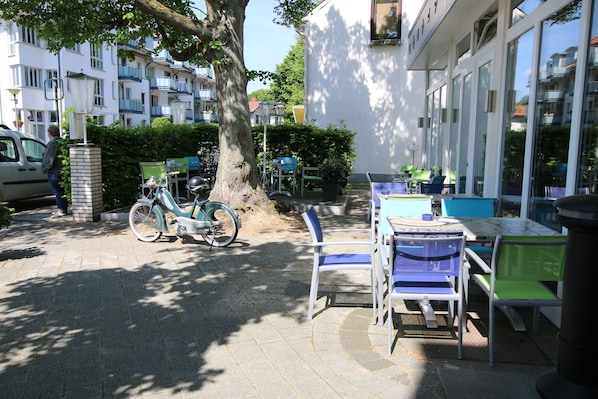 Un espacio al aire libre con mesas, sillas, una bicicleta y un árbol.