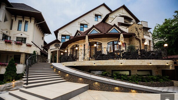 A hotel with a grand entrance, a stone staircase, and a well-lit outdoor area. - VisPas Hotel (Chisinau)