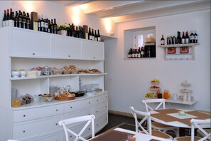 Montaje de un bufé de desayuno con diferentes alimentos y botellas de vino en estantes.