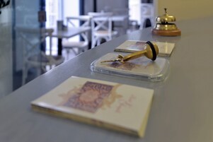 A table with a clear plastic container holding a gold-colored object, possibly a pen or tool, and a book with a decorative cover.