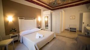 Una habitación de hotel con una cama grande, una mesita de noche, una silla, un armario y un espejo.
