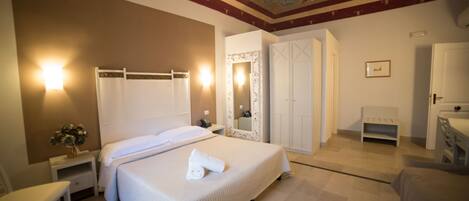 A hotel room with a large bed, a bedside table, a chair, a wardrobe, and a mirror.