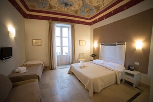 A hotel room with two beds, a television, a desk, and a large window.