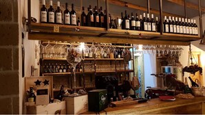 A bar area with multiple shelves of wine bottles, glasses, and a jukebox. - Hotel Meublè Santa Chiara Suite (Naples)