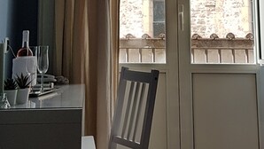 A room with a large window, a chair, a table with a bottle and glasses, and a TV mounted on the wall. - Hotel Meublè Santa Chiara Suite (Naples)