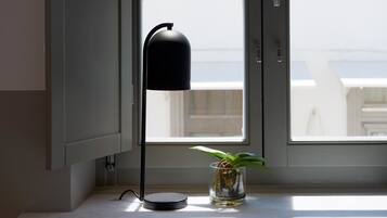 Una habitación moderna con una lámpara de pie y una planta pequeña en el alféizar de una ventana.