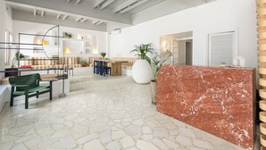 Un hall d’entrée spacieux avec un comptoir de réception en marbre, des espaces de détente et un design moderne au niveau du plafond.