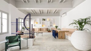 Un salon moderne avec un canapé, une table à manger et un grand pot de fleurs blanc.