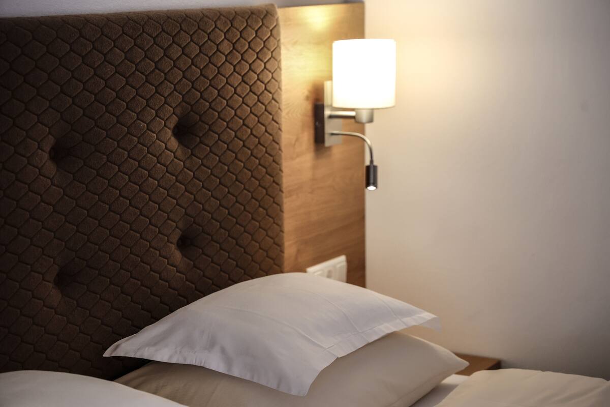 A bed with a textured headboard and a wall-mounted light fixture.