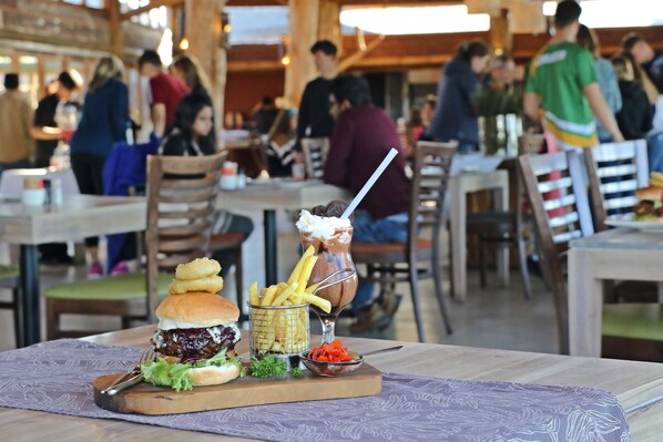 A restaurant setting with a burger, fries, and a milkshake on a table. - Garden Route Game Lodge (Albertinia)