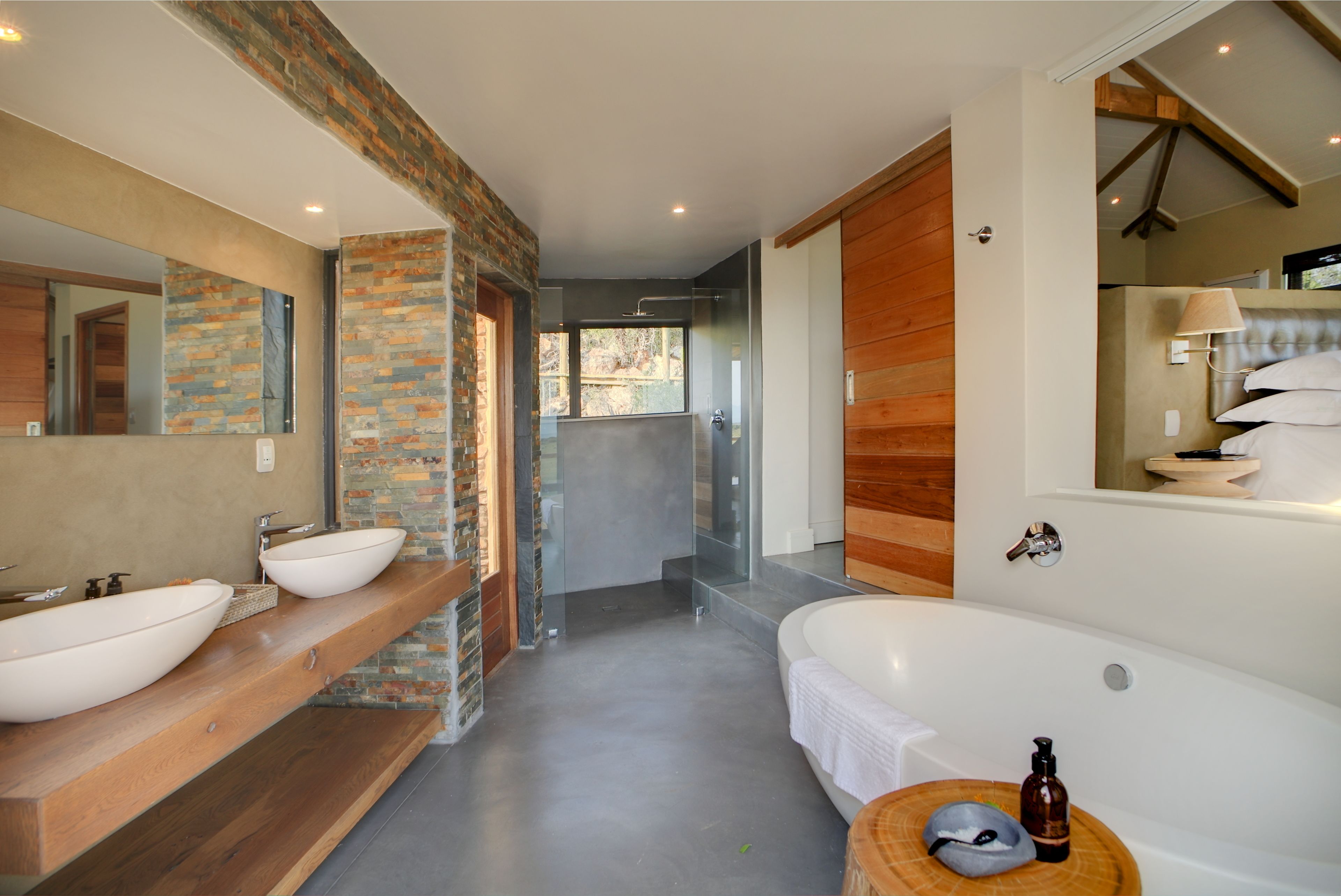 Une salle de bain moderne avec une grande baignoire, deux lavabos, un miroir et un meuble-lavabo en bois.