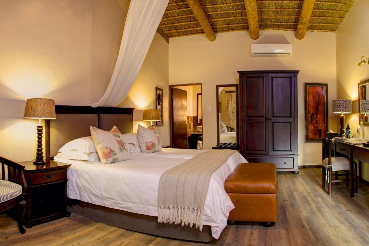 A bedroom with a bed, bedside tables, a chair, a desk, and a wardrobe.