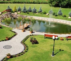 A landscaped garden with a pond, a wooden bridge, and a pathway. - Dworek Hetmanski (Stargard Szczecinski)