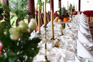 A table set with white napkins, gold candle holders, and a fruit centerpiece. - Dworek Hetmanski (Stargard Szczecinski)