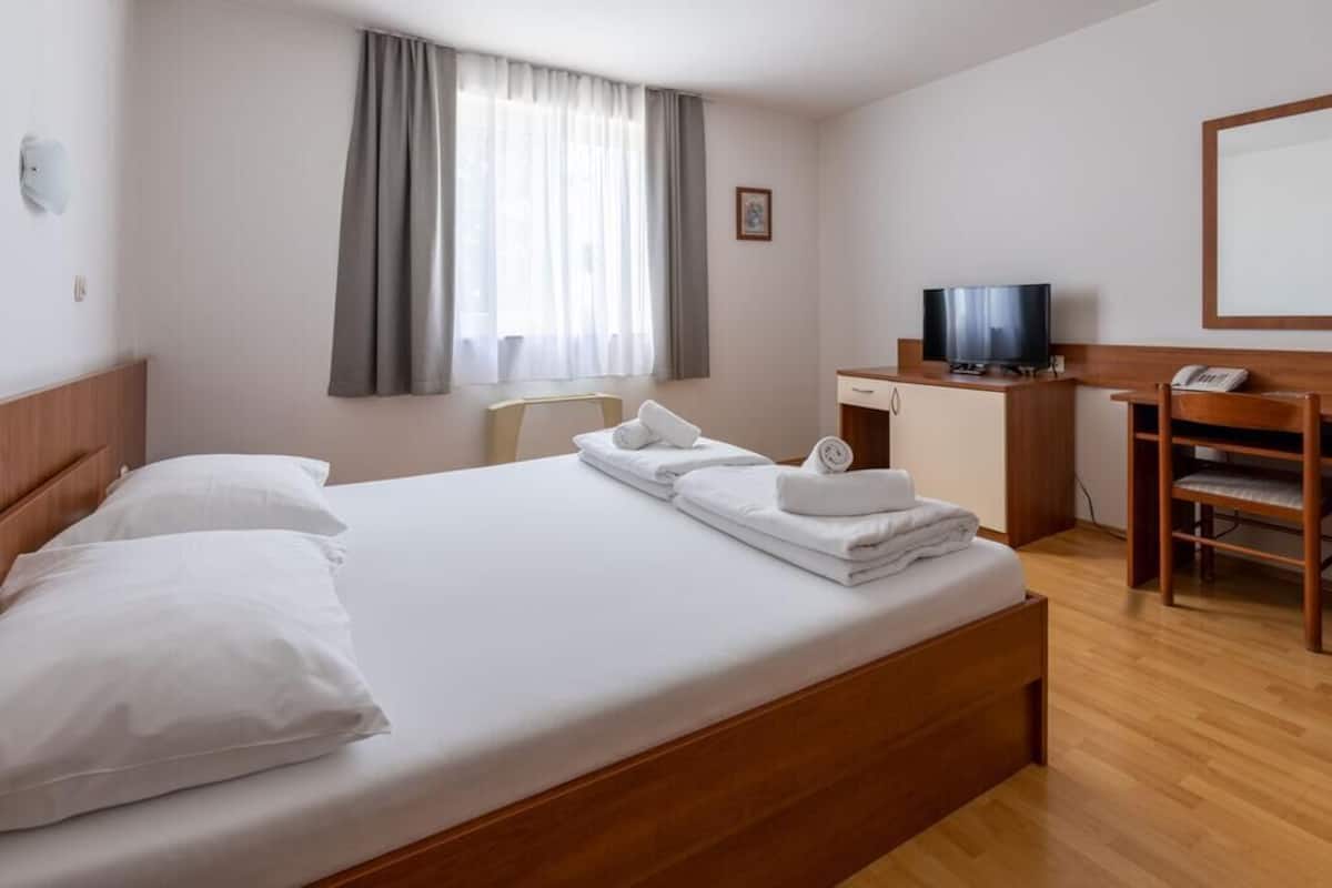 Une chambre d’hôtel équipée d’un lit, d’un bureau, d’une télévision et d’une chaise.
