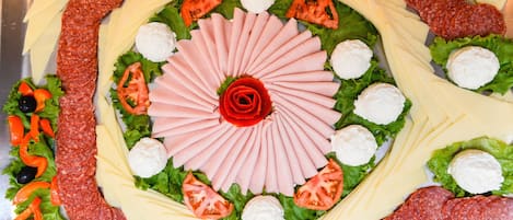 Eine Platte mit verschiedenen Fleisch-, Käse- und Gemüsesorten, kunstvoll angerichtet.