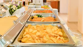 En buffet med forskellige retter i metalbakker, blandt andet kartofler og en tomatbaseret ret.